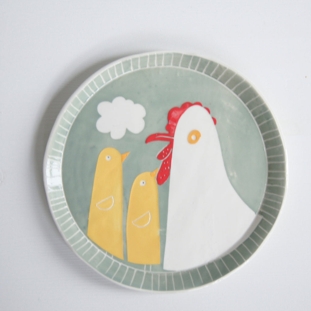 Round plate with a design of two yellow ducks and a red rooster on a light gray background
